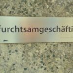Edelstahlplatte an Betonmauer mit dem Schriftzug "furchtsamgeschäftig"